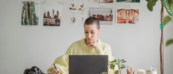 Creative professional designing best-selling Canva templates at home office with laptop, camera, and inspiration wall photos